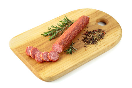 Sliced salami on a cutting board. Sausage with rosemary and spices isolated on a white background.の写真素材
