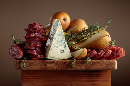 Blue cheese, dry-cured sausages, thyme and pears on a wooden table.の写真素材