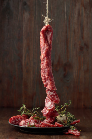 Dry-cured sausages with thyme and garlic on an old wooden table.の写真素材