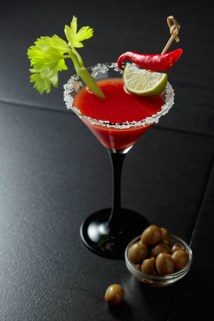 Bloody Mary cocktail with celery, lime, red pepper, and green olives. The glass is decorated with sea salt.の写真素材