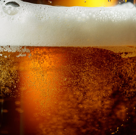 Glass of beer with foam, closeup. Pouring beer with bubble froth in glass for background and design.の写真素材