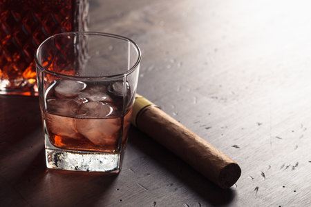 Glass of whiskey with ice on an old wooden table.の写真素材