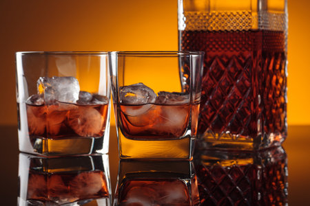 Whiskey with ice on a black reflective background.の写真素材