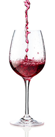 Pouring red wine into a glass. Isolated on a white background.の写真素材