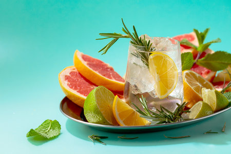 A refreshing summer drink with ice, citrus, rosemary and mint. Green background with copy space.の写真素材