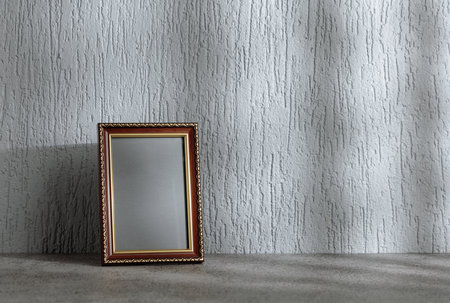 Empty picture frame on a gray background. Wooden frame with golden ornament. Place your image in the frame. Copy space.の写真素材
