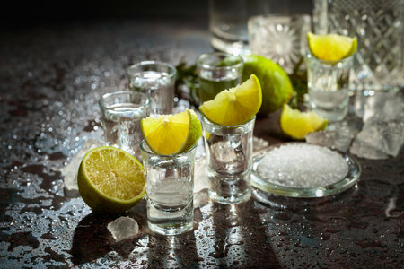 Tequila with lime, sea salt, and crushed ice on a wet vintage background.の写真素材