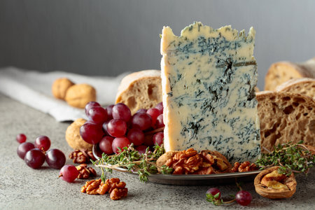 Gorgonzola with ciabatta, walnuts, grapes, and thyme on a gray stone background. Copy space.の写真素材