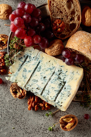 Gorgonzola with ciabatta, walnuts, grapes, and thyme on a gray stone background. Top view.の写真素材