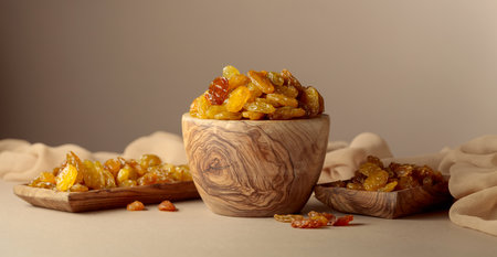 Yellow sultana raisins in a wooden bowl on a beige background. Copy space.の写真素材