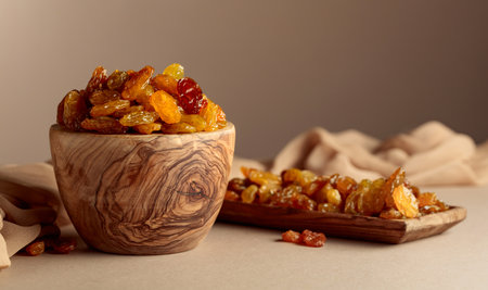 Yellow sultana raisins in a wooden bowl on a beige background. Copy space.の写真素材