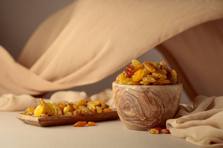 Yellow sultana raisins in a wooden bowl on a beige background. Copy space.の写真素材