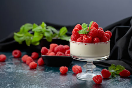Mascarpone cream with fresh raspberries in a clear bowl. Berry parfait delight garnished with mint...