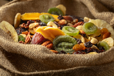 Dried tropical fruits, nuts, and raisins in burlap bag.の写真素材