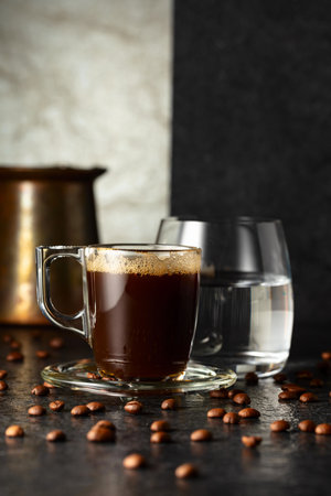 Espresso, glass of cold water, and roasted coffee beans on a black stone background. Copy space.の写真素材