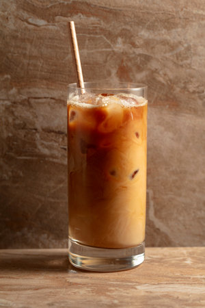 Iced coffee with cream, refreshing and sweet coffee drink on a beige ceramic table.の写真素材