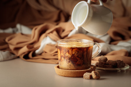 Pouring cream in black coffee. Latte preparing.の写真素材