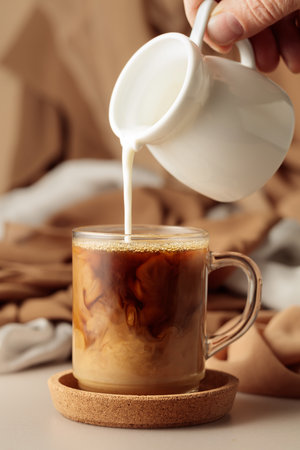 Pouring cream in black coffee. Latte preparing.の写真素材
