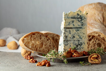 Gorgonzola with ciabatta, walnuts, and thyme on a gray stone table. Copy space.の写真素材