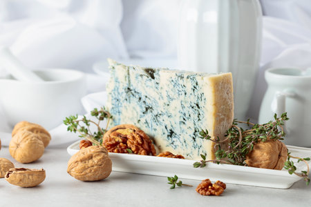 Gorgonzola cheese with walnuts, and thyme on a white kitchen table.の写真素材