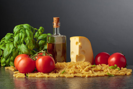Ingredients for preparing traditional Italian pasta. Fusilli pasta, tomatoes, basil, olive oil and cheese. Copy space.の写真素材