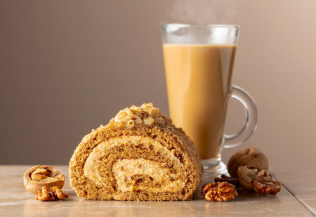 Walnut and buttercream roll: a traditional Oriental pastry. Dessert with walnuts and coffee latte on a beige background. Cake with brown sugar, walnuts, and cream. Copy space.の写真素材