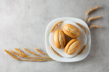 French buns and wheat ears on a marmoreal table. Top view. Copy space.の写真素材