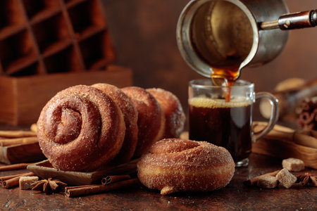 Swedish cinnamon rolls and black coffee on a brown background. Coffee is poured into a glass mug.の写真素材