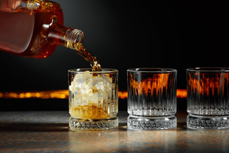 Whiskey is poured into a glass with ice. Copy space.