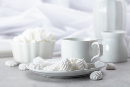 White vanilla meringue and coffee cup on a white marble table.の写真素材
