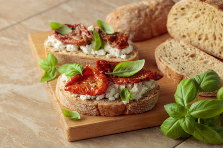 Ciabatta with sun dried tomatoes in olive oil, ricotta, and basil. Traditional Italian snack on a...