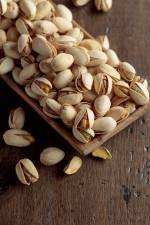 Salted pistachios in a dish on an old wooden table.