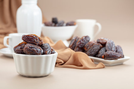Dried medjool dates in white dish on a beige background.