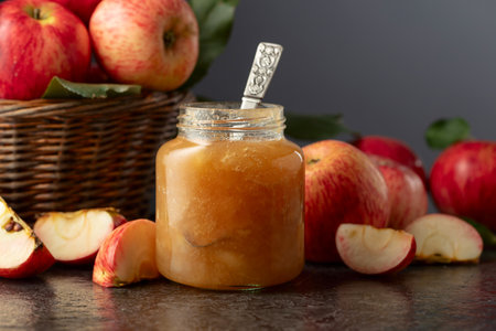 Apple jam and red fresh apples on a black stone table. Copy space.