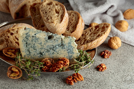 Gorgonzola with ciabatta, walnuts, and thyme on a gray stone table.の写真素材