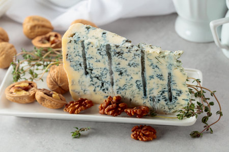 Gorgonzola cheese with walnuts, and thyme on a white kitchen table.の写真素材