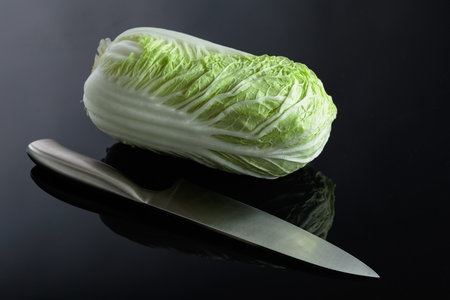 Fresh Chinese cabbage and knife on a black reflective background.の写真素材