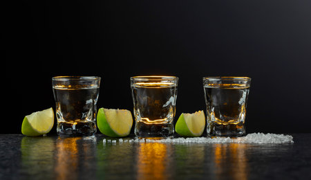Mexican Tequila with lime and salt on a stone table. Dark background with copy space.