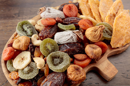 Dried mango slices, tropical fruits, nuts, and raisins on an old wooden table. Top view.