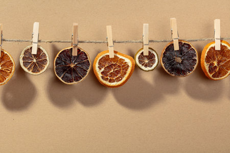 Orange slices are dried on a line. Bright sunlight and shadows on a beige background. Copy space.