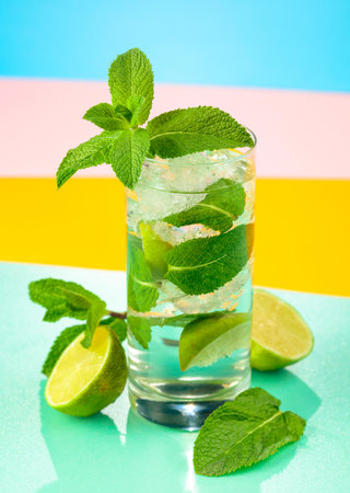 Mojito cocktail with ice, lime and mint. Bright colorful background.