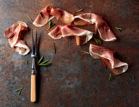 Prosciutto with rosemary on vintage background. Traditional Mediterranean snack. Top view.の写真素材