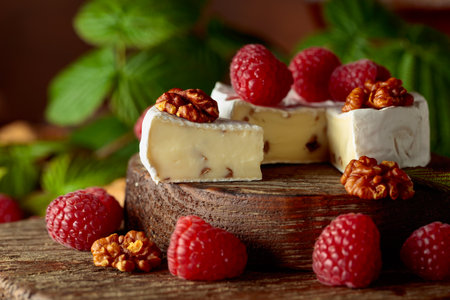 Camembert cheese with fresh raspberries and walnuts on a brown vintage table.の写真素材