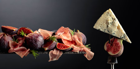 Prosciutto with blue cheese, rosemary, and fig on a black background. Copy space.の写真素材