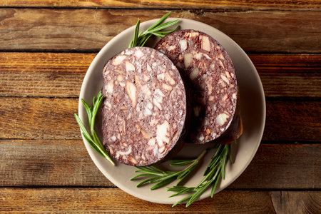 Blood sausage with pieces of meat on an old wooden table.の写真素材