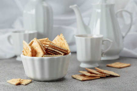 Crunchy square crackers and black coffee. Gray stone table and white utensils.の写真素材