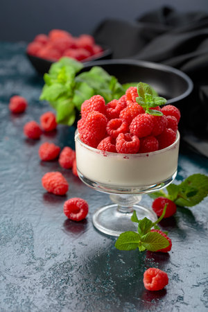 Panna cotta with fresh raspberries in a clear bowl. Berry parfait delight garnished with mint...