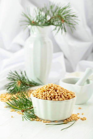 Peeled pine nuts on a white wooden table. Pine nuts in white dish on a white background.の写真素材