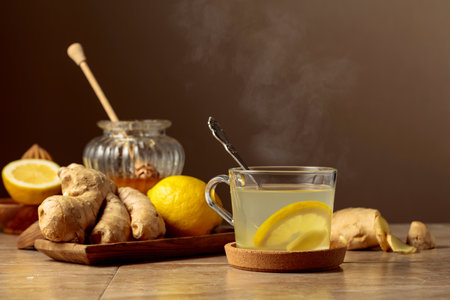 Ginger tea with lemon and honey on a beige kitchen table.の写真素材