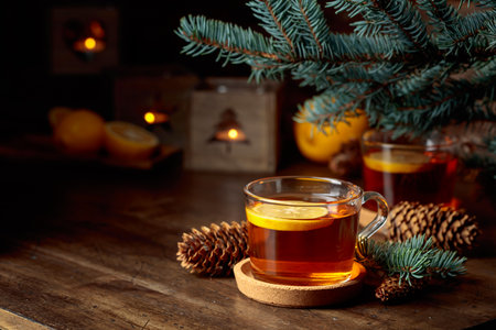Tea with lemon and small Christmas lanterns with burning candles on a wooden table.の写真素材